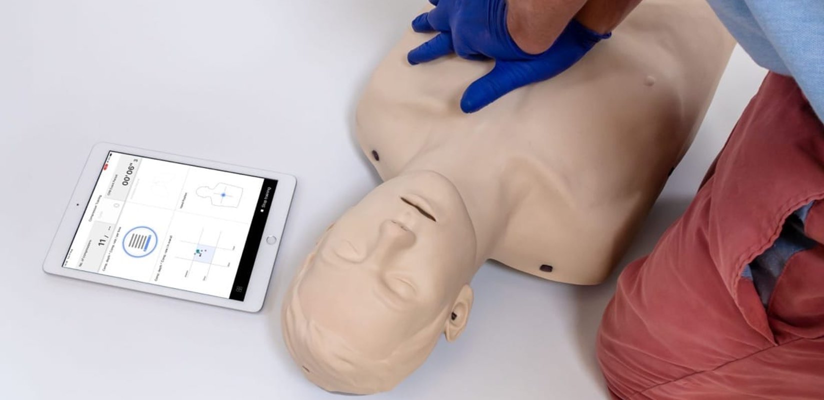 Student performing chest compressions on a Brayden Pro manikin with the feedback app running on a tablet