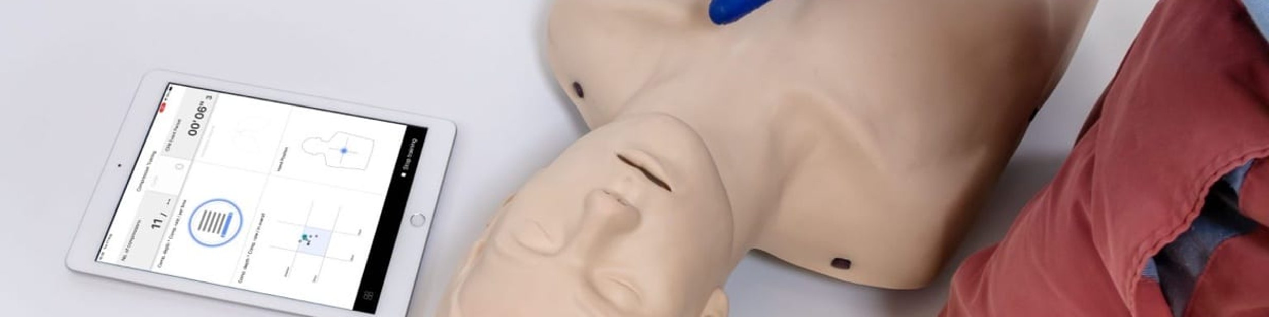Student performing chest compressions on a Brayden Pro manikin with the feedback app running on a tablet